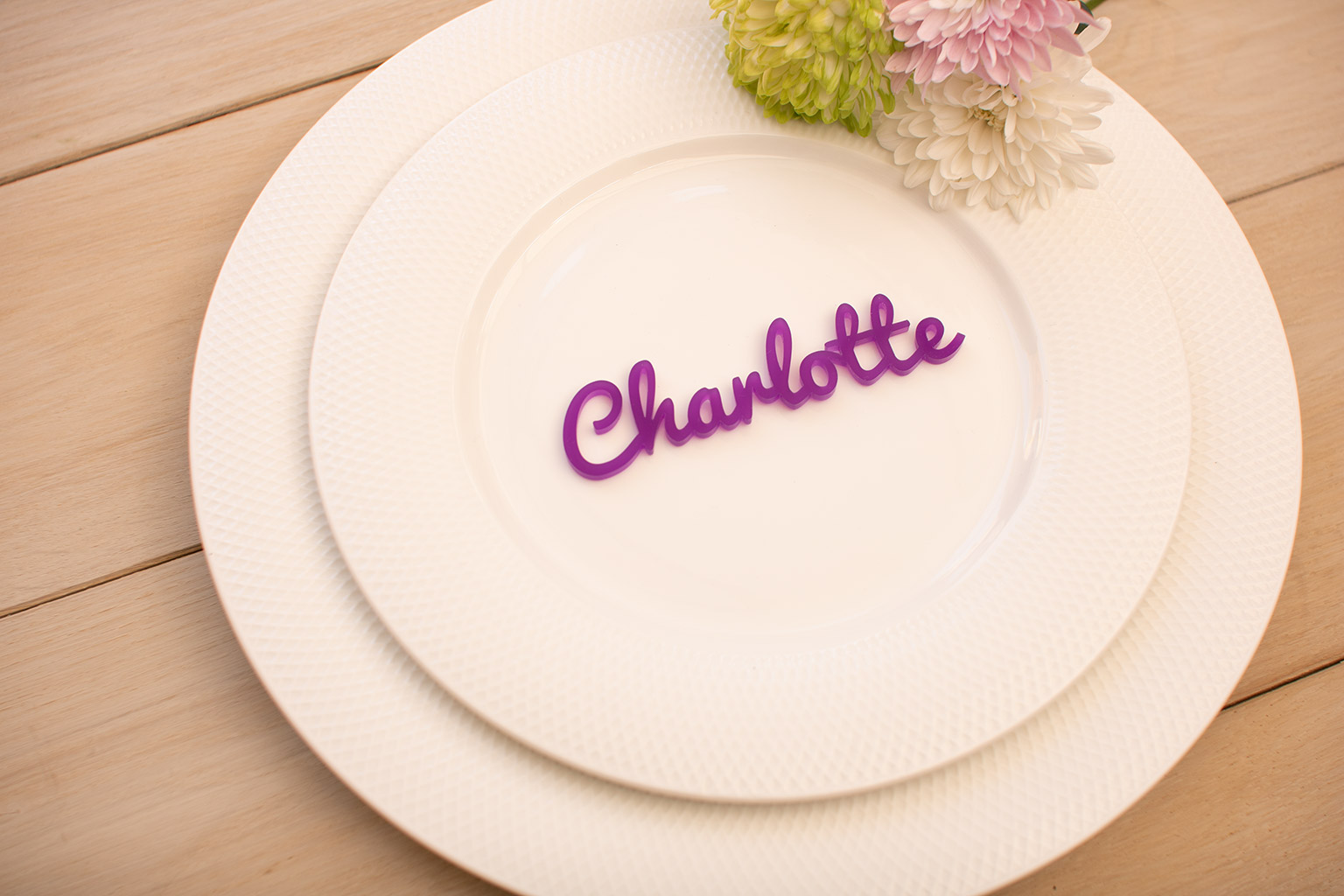 a purple acrylic wedding place name on a white plate.